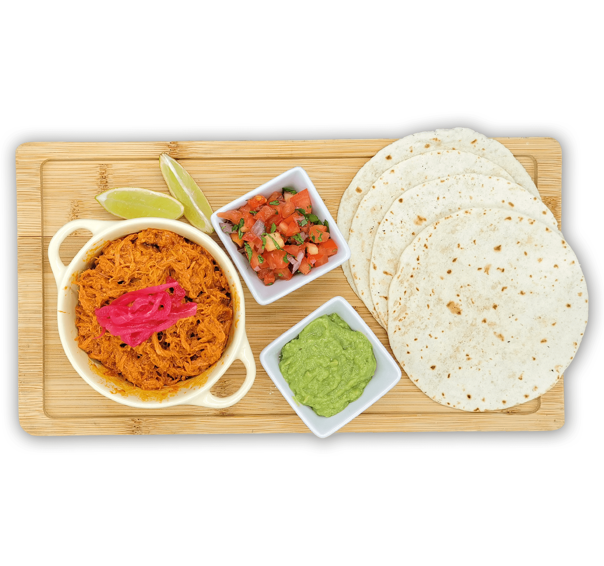 Una bandeja de madera contiene una porción de Tacos de Cochinita Pibil en un tazón, acompañados de dos gajos de limón, un plato pequeño de tomates y cebollas cortados en cubitos, un plato pequeño de guacamole y cuatro tortillas de harina, todo perfectamente dispuesto para crear sabrosos tacos.